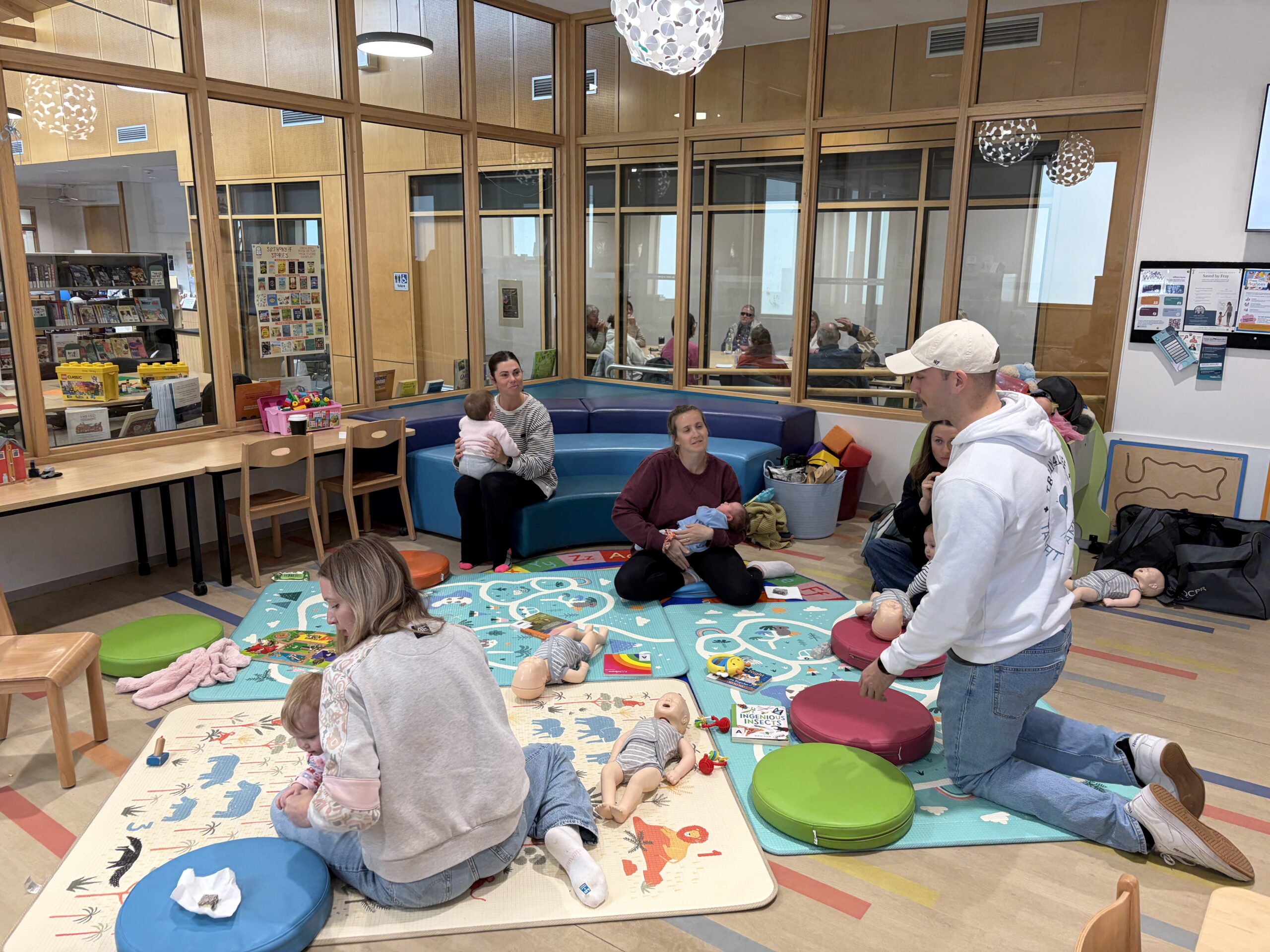 Aaron from Train4Life kneeling and demonstrating infant CPR on a training manikin during a community workshop